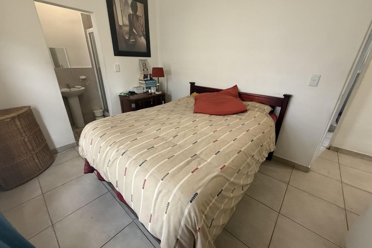 A bedroom featuring tiled flooring and an en-suite bathroom with a pedestal basin.