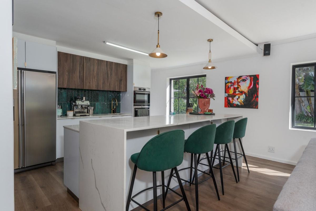 Modern kitchen featuring a large quartz-topped island, sleek cabinetry, built-in appliances, and a stylish tiled backsplash, creating a functional and contemporary culinary space.