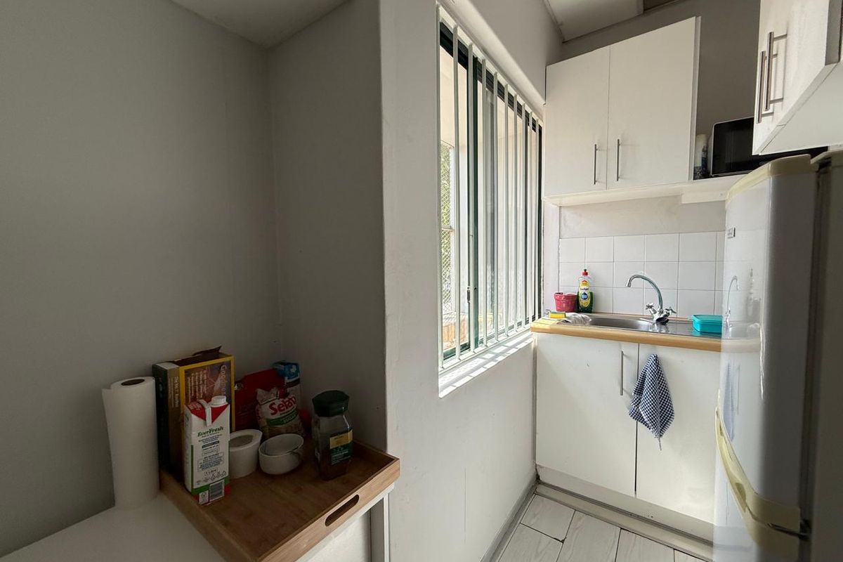Compact kitchenette featuring white cabinetry, stainless steel sink, and tiled flooring, providing a functional prep area within the office space.