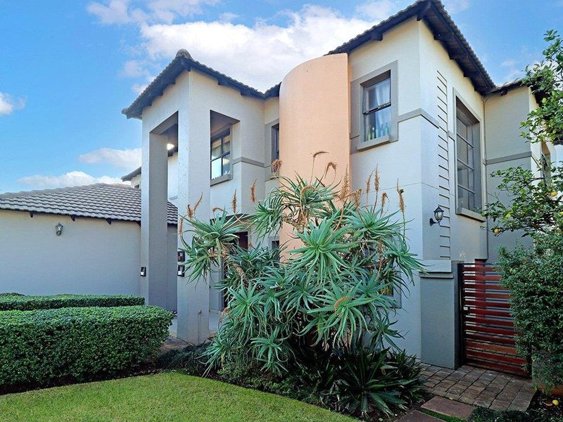 A well-maintained double-story residential property featuring a modern facade, tiled roof, and landscaped front garden with established greenery.