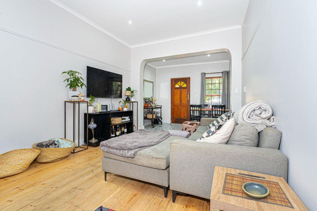 A bright living room featuring original timber flooring, a classic archway leading to the entrance, and recessed downlighting throughout the space.