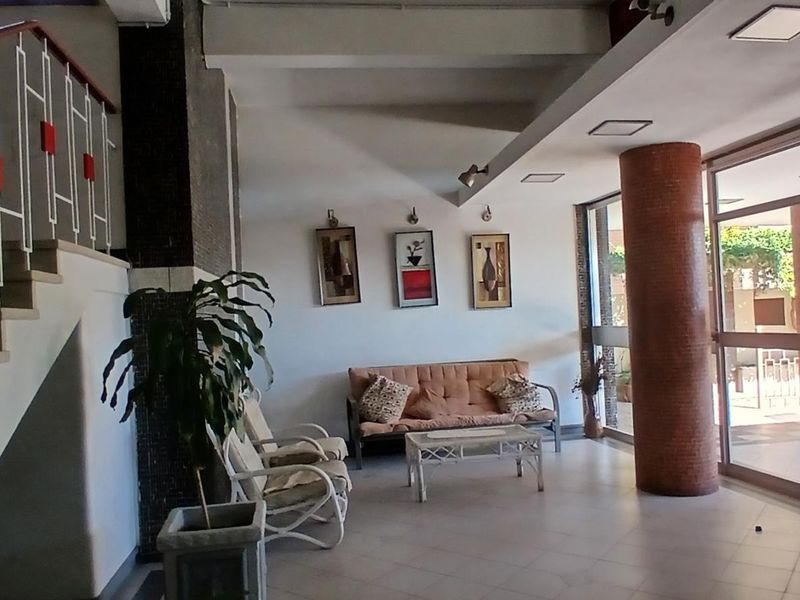 A spacious apartment building entrance lobby featuring tiled flooring, a staircase with a decorative metal railing, and large glass doors leading outside.