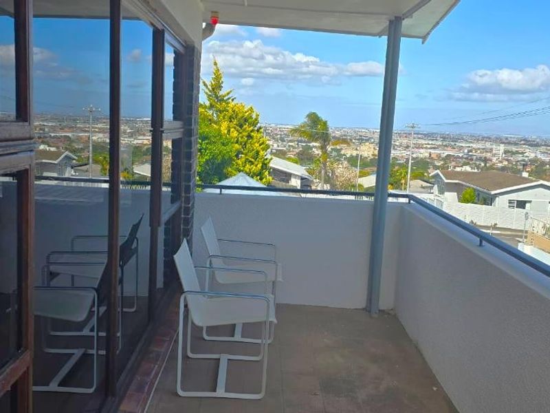 A covered balcony featuring tiled flooring, a metal safety railing, and expansive views of the surrounding neighborhood.