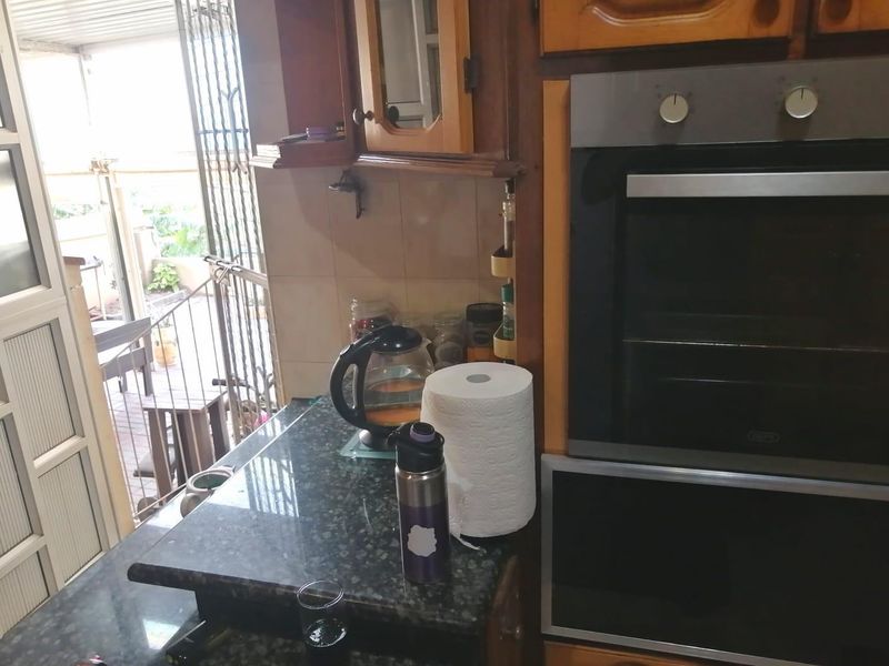 A kitchen area featuring wooden cabinetry, a built-in oven, and granite countertops, with direct access to an outdoor patio area.