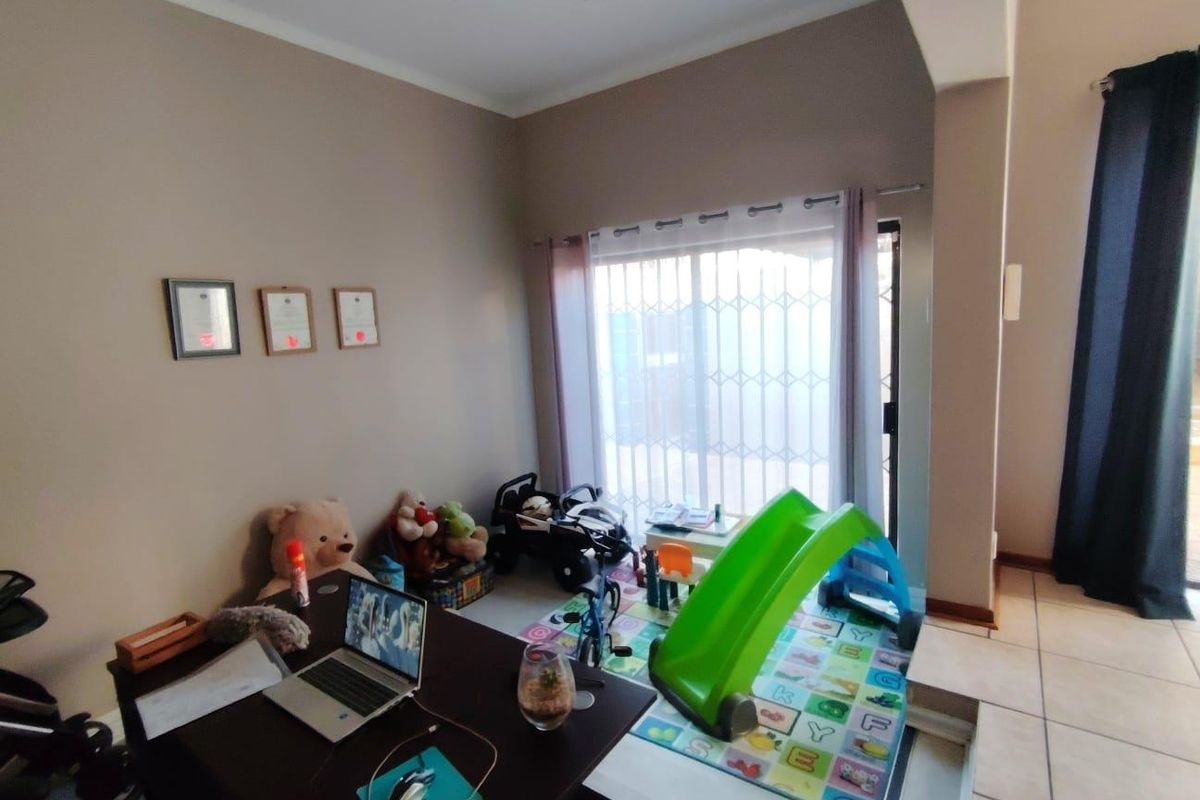 A versatile living space featuring tiled flooring and sliding glass doors with security gates, providing direct access to the outdoor area.