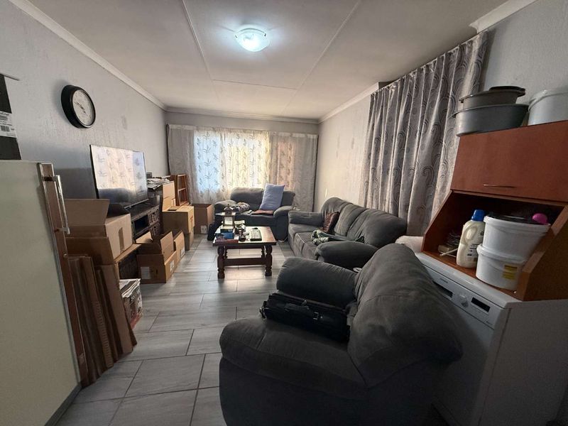 A living room area featuring tiled flooring and neutral wall finishes, currently utilized as a multi-purpose living space.