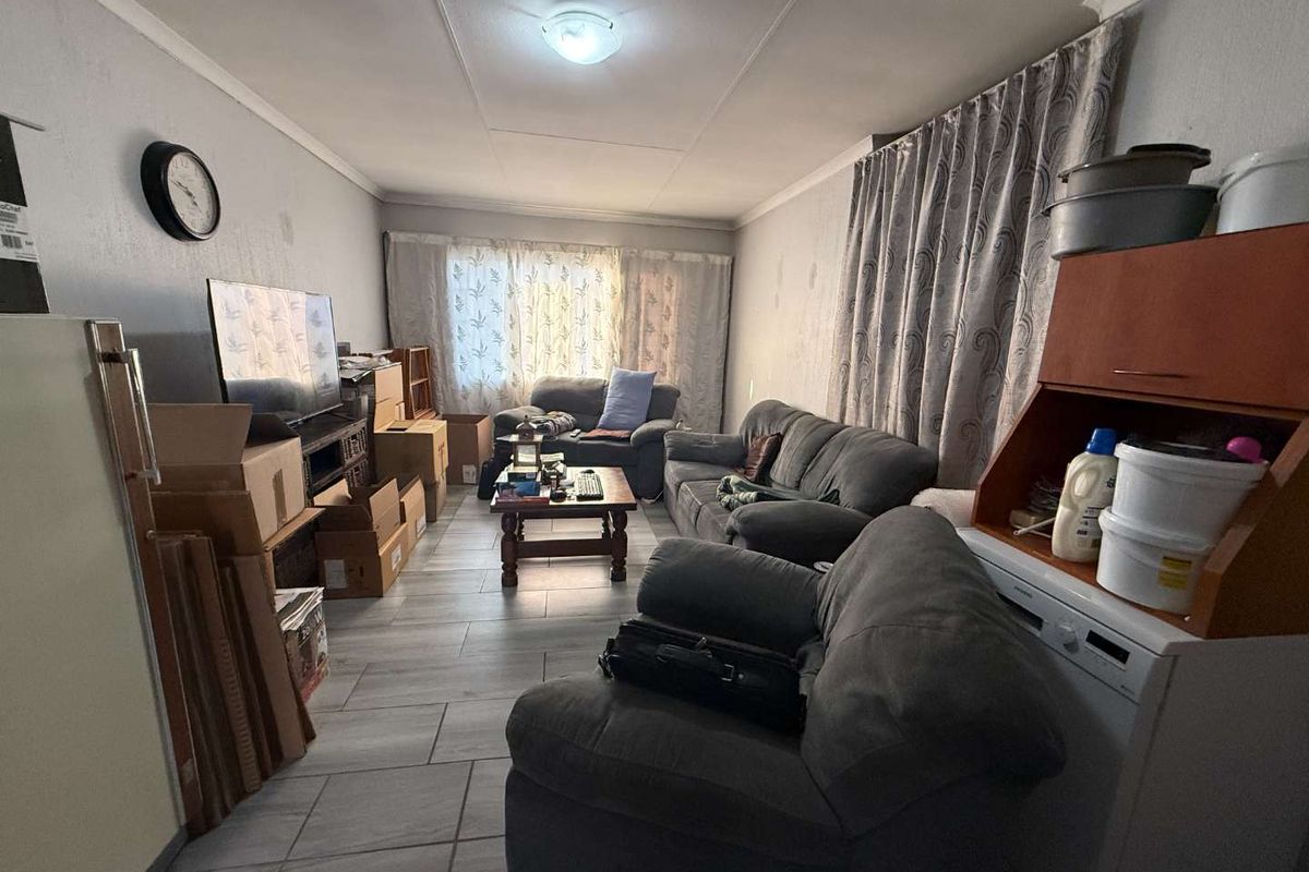 A living room area featuring tiled flooring and neutral wall finishes, currently utilized as a multi-purpose living space.