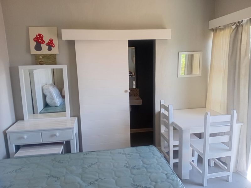 A bedroom featuring a white sliding barn door leading to an en-suite bathroom, with neutral wall finishes and natural light from the window.