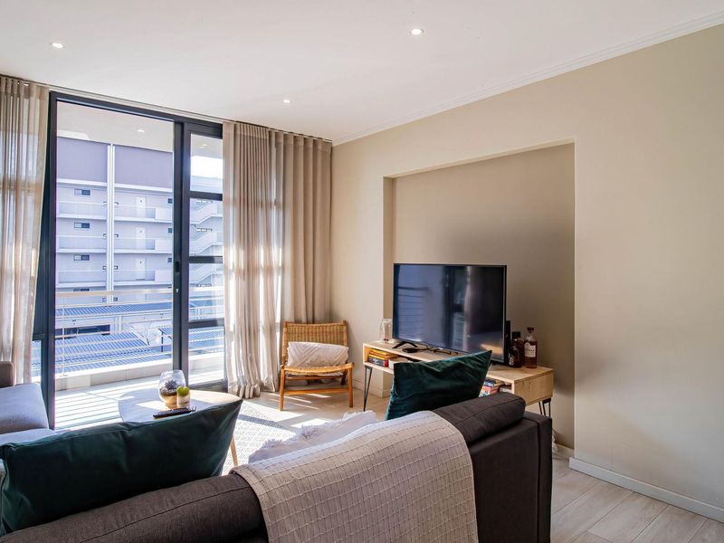 A bright and modern living room featuring large sliding glass doors that open onto a private balcony, providing ample natural light.