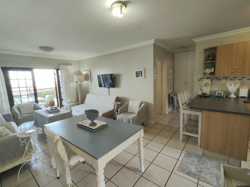 Open-plan living and kitchen area featuring tiled flooring, a breakfast bar, and sliding glass doors leading to an outdoor space.