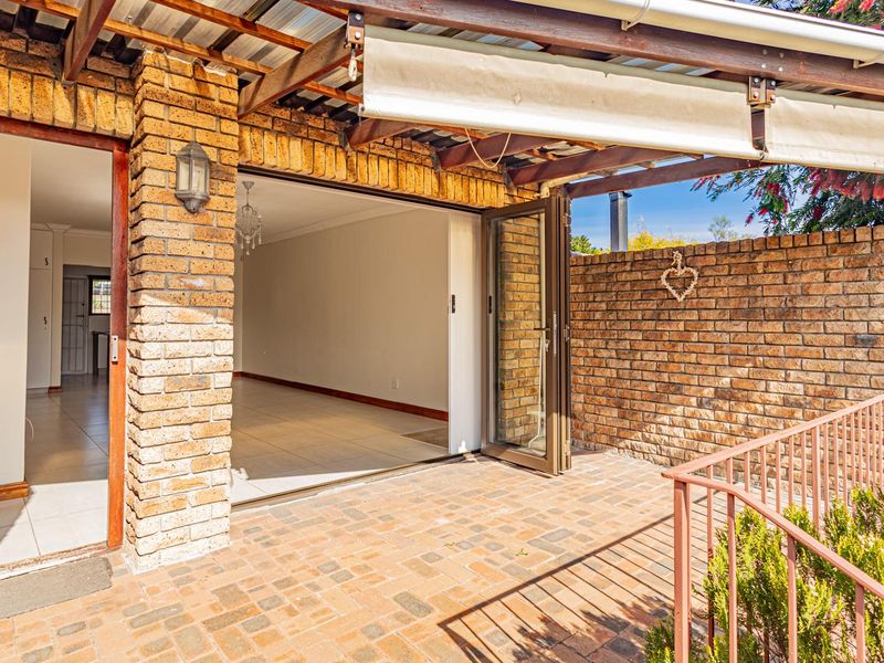 Covered outdoor patio featuring exposed brick walls, timber pergola, and folding glass doors providing seamless access to the interior living space.