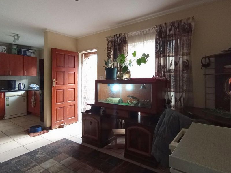 Open plan living area featuring tiled flooring and an adjoining kitchen with built-in cabinetry.