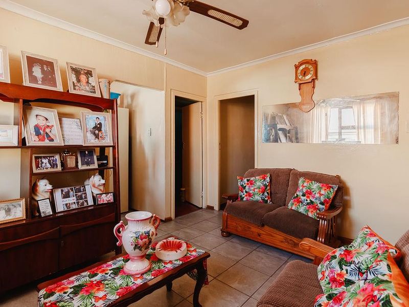 A living room featuring tiled flooring, a ceiling fan, and coved cornicing, offering a functional space with potential for modern updates.