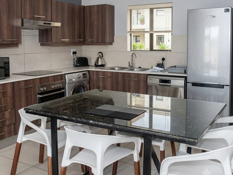 Modern kitchen featuring dark wood cabinetry, granite countertops, integrated appliances, and a central dining island with tiled flooring throughout.