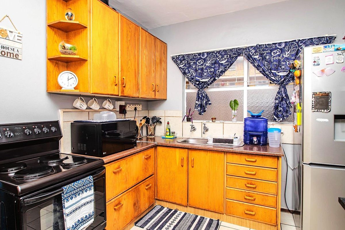 A functional kitchen featuring wooden cabinetry, a stainless steel sink, and a freestanding stove, offering a practical layout for daily meal preparation.