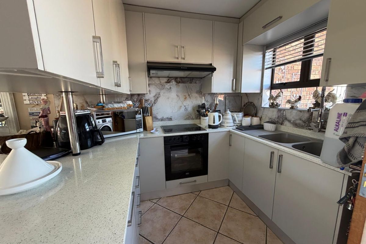 A functional kitchen featuring modern cabinetry, stone countertops, a marble-look splashback, and integrated appliances including an electric hob and oven.