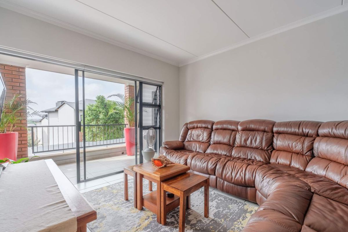 A bright living room featuring large sliding glass doors that open onto a private balcony, providing natural light and seamless indoor-outdoor flow.