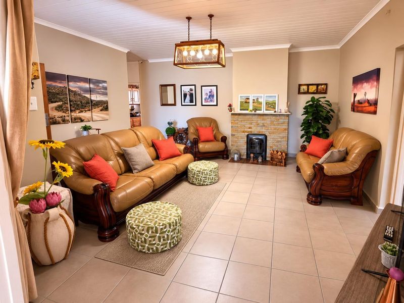 A comfortable living room featuring a stone-surround fireplace, neutral tiled flooring, and a classic tongue and groove ceiling with a central pendant light.