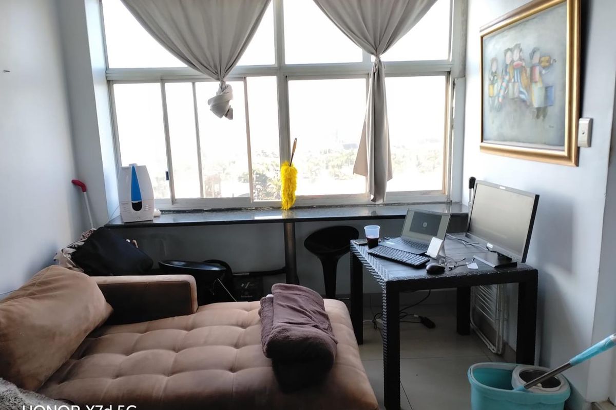 A functional living area featuring large windows with natural light, tiled flooring, and a built-in window ledge.