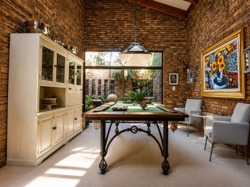 Spacious living area featuring striking exposed brick walls, a high vaulted ceiling, and large glass doors providing natural light and garden views.