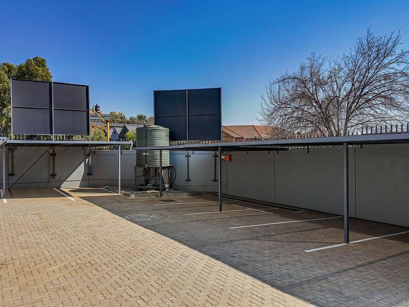 A well-maintained outdoor parking area featuring covered bays, paved surfacing, and a water storage tank within a secure perimeter.