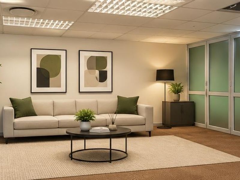 A professional office space featuring modern frosted glass partitions, suspended ceiling with recessed lighting, and neutral carpet flooring.