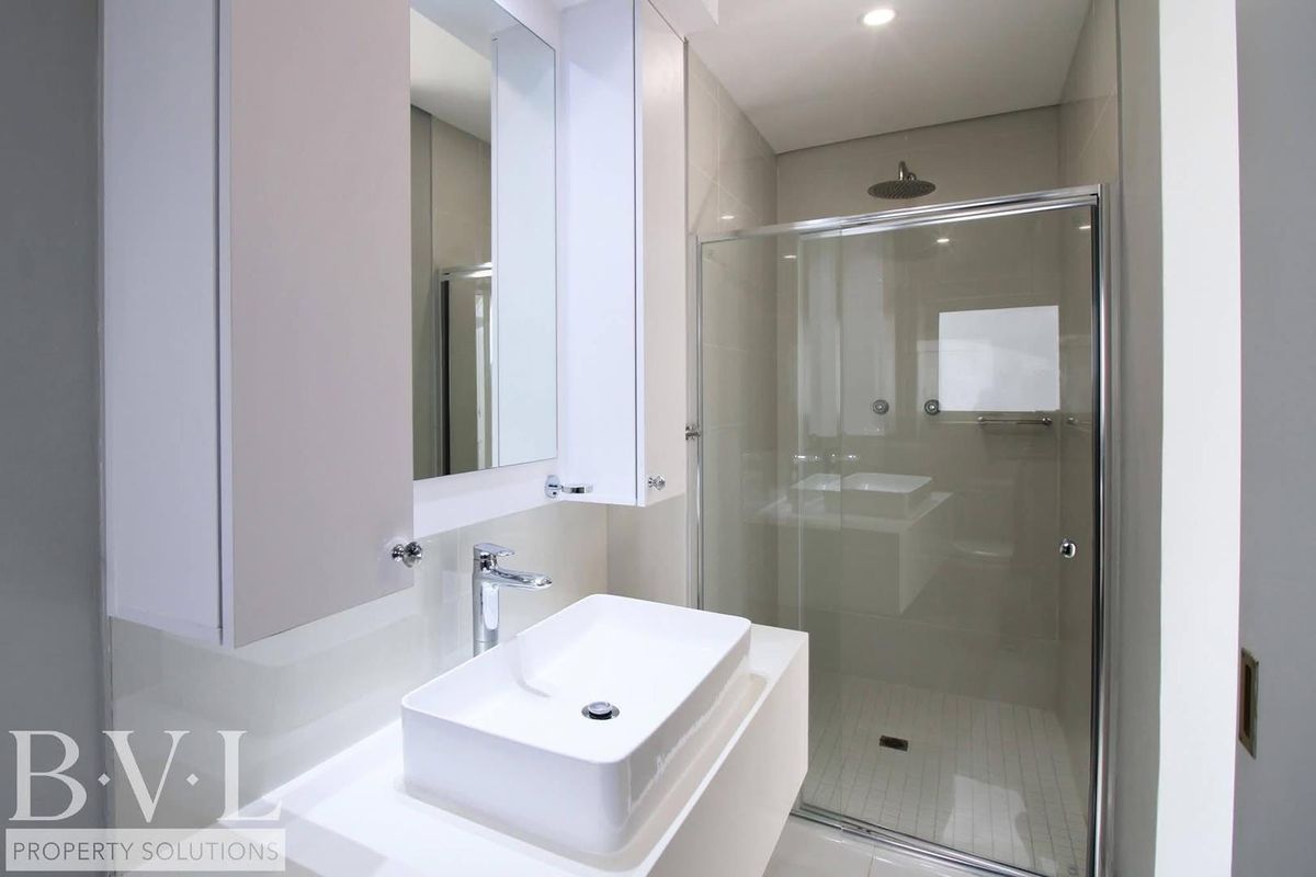 Modern bathroom featuring a floating vanity with a vessel sink, a wall-mounted mirror cabinet, and a glass-enclosed walk-in shower with a rainfall showerhead.