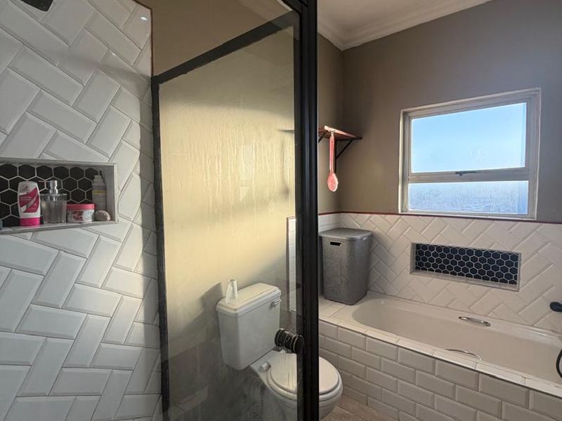Modern bathroom featuring a glass-enclosed shower with subway tiles, a built-in bathtub, and stylish hexagonal mosaic accents.