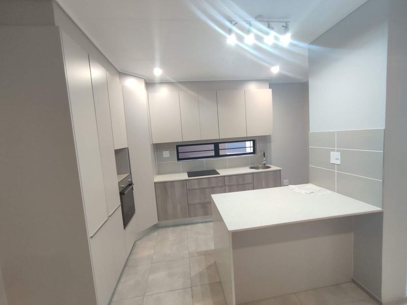 Modern kitchen featuring sleek built-in cabinetry, stone countertops, a central island, and integrated appliances, finished with contemporary tiled flooring and recessed lighting.