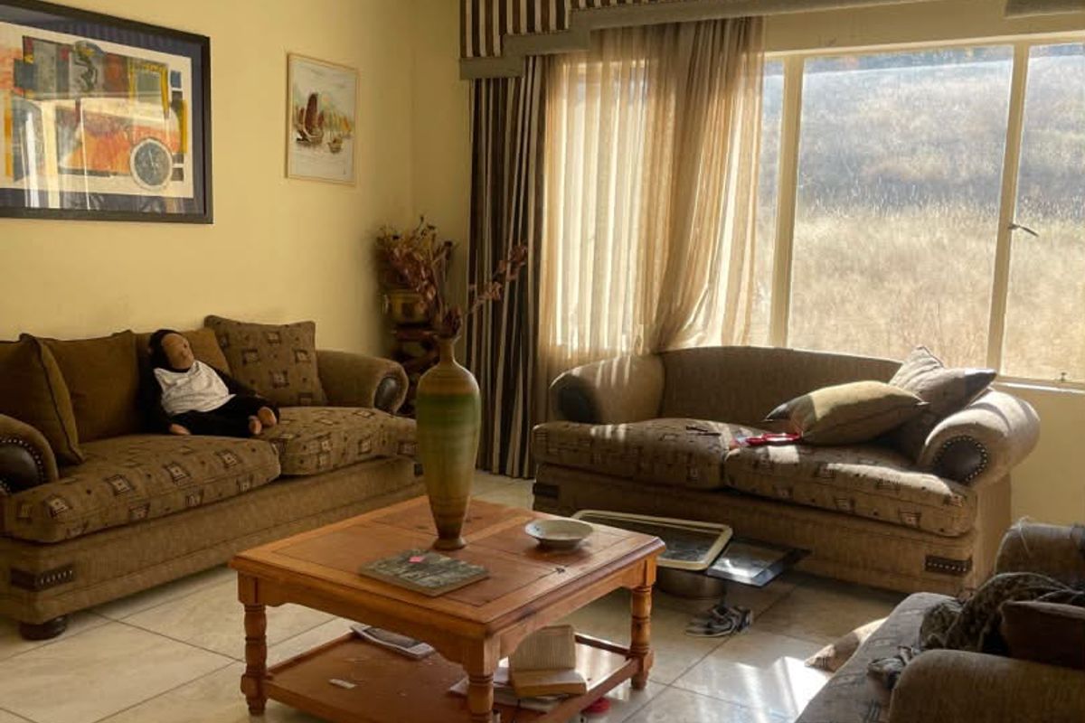 A spacious living room featuring large windows, tiled flooring, and recessed downlighting, offering a bright and comfortable area for relaxation.