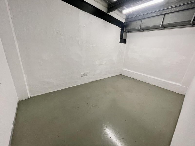 A functional, empty utility space featuring painted concrete flooring, exposed industrial steel beams, and overhead fluorescent lighting.