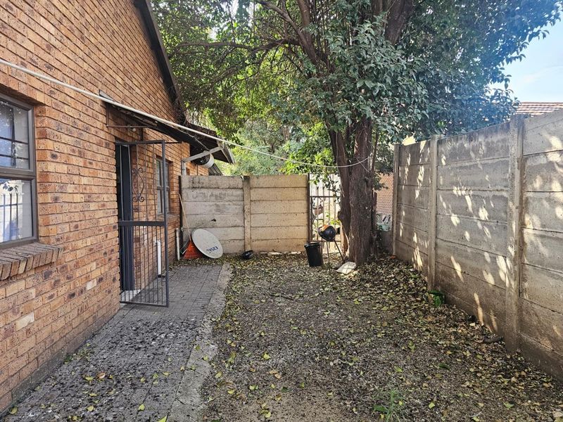 A rear exterior view of the property featuring a face brick facade, paved walkway, and precast concrete boundary walls.
