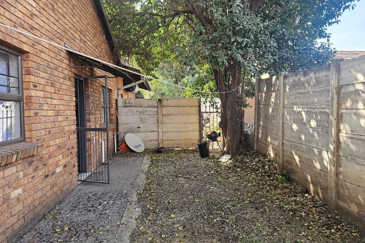A rear exterior view of the property featuring a face brick facade, paved walkway, and precast concrete boundary walls.