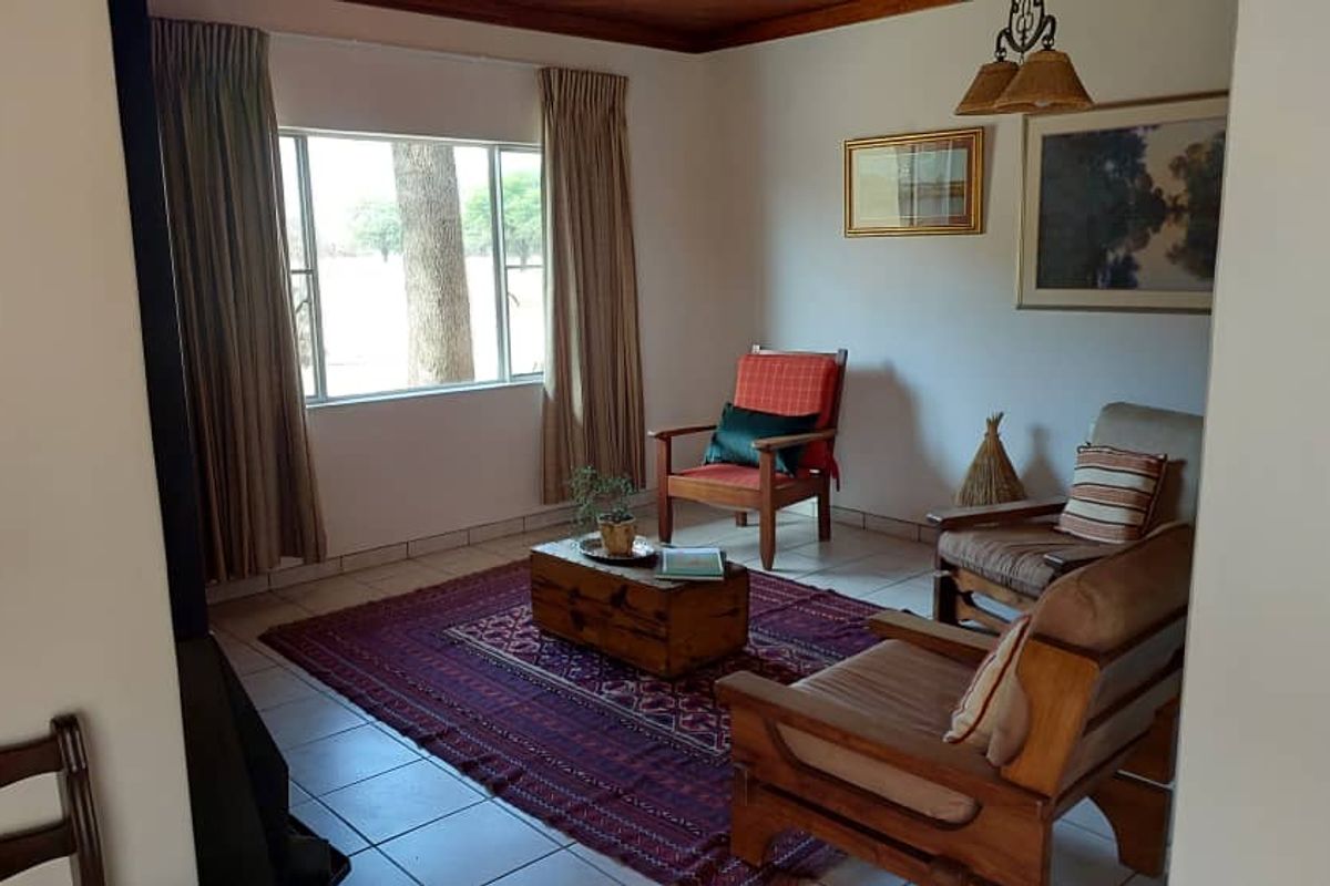 A cozy living room featuring tiled flooring, large windows with natural light, and a warm, inviting atmosphere suitable for relaxation.