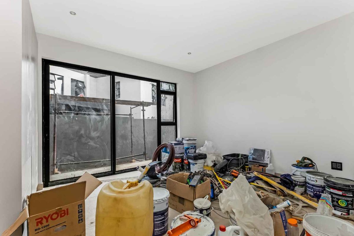 A bright, unfinished room featuring large black-framed sliding glass doors leading to an exterior area, suitable for a bedroom or living space.