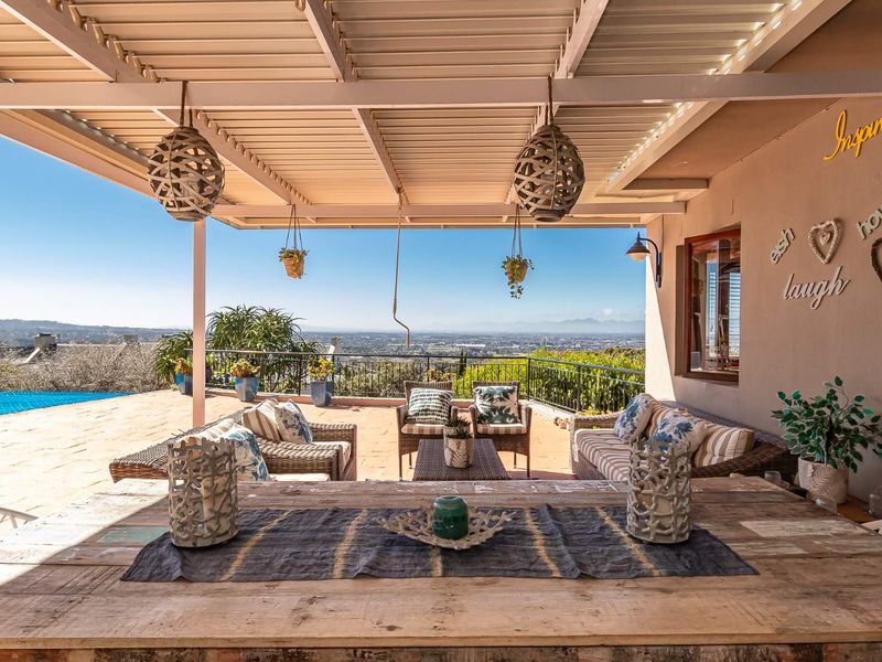 A spacious covered patio featuring tiled flooring, a metal roof structure, and wrought iron railings, offering expansive views of the surrounding landscape.