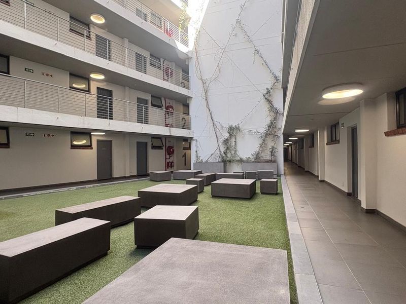 A well-maintained apartment complex courtyard featuring artificial turf, concrete seating blocks, and multi-level access balconies with recessed lighting.