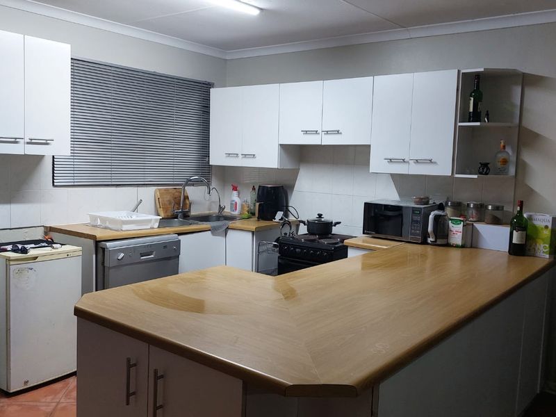 A functional kitchen featuring white cabinetry, laminate countertops, a tiled backsplash, and a breakfast bar area.