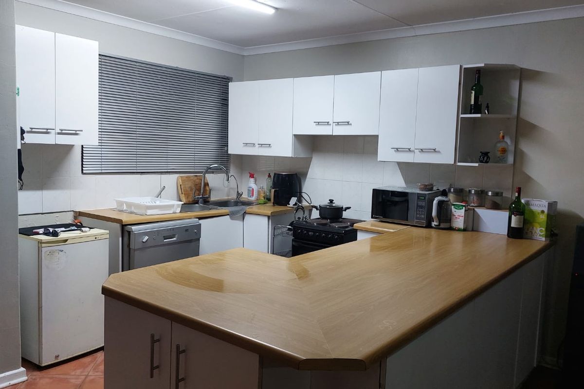 A functional kitchen featuring white cabinetry, laminate countertops, a tiled backsplash, and a breakfast bar area.