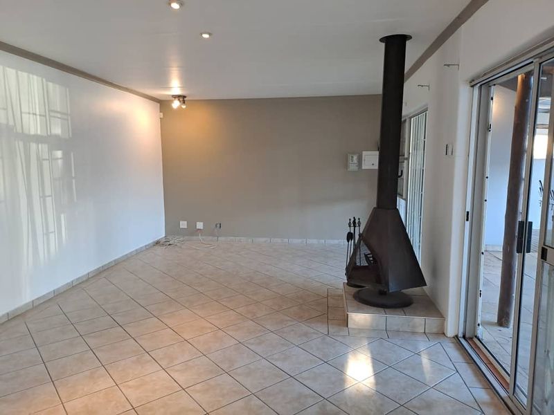 Spacious living area featuring tiled flooring, a prominent freestanding fireplace, and large sliding glass doors providing access to the outdoor space.