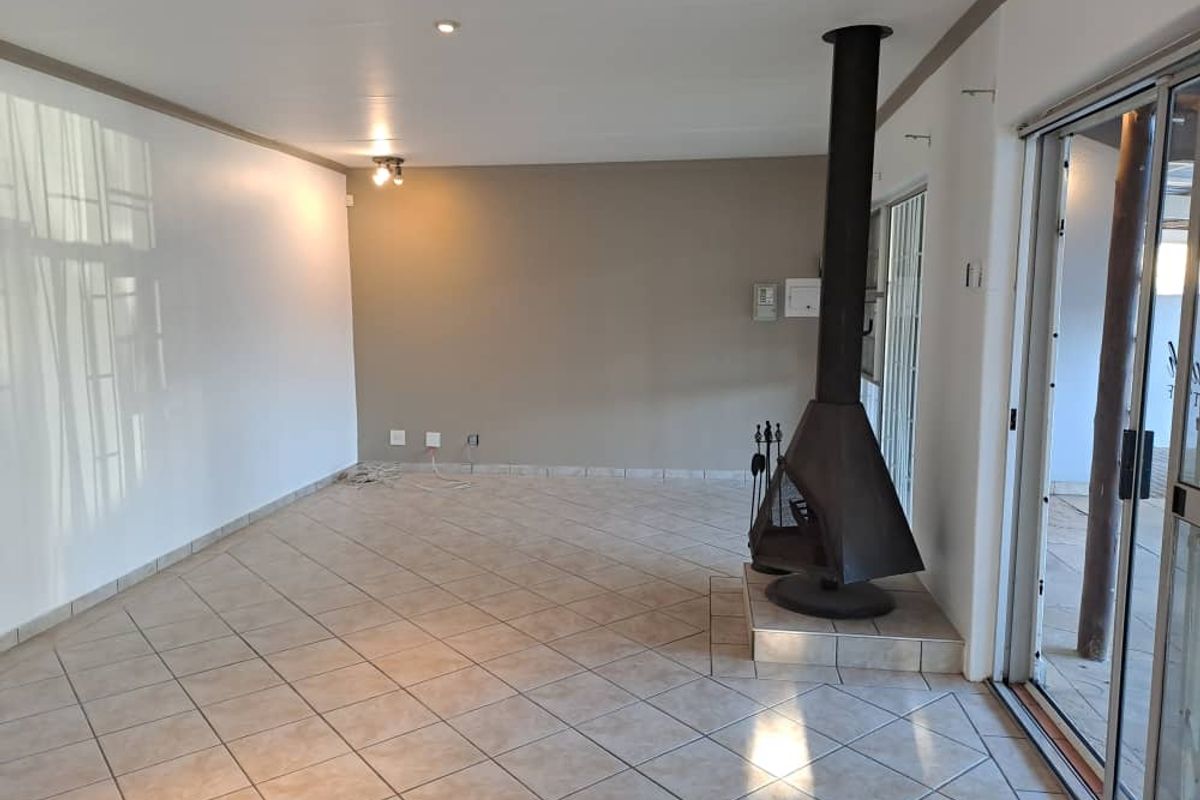 Spacious living area featuring tiled flooring, a prominent freestanding fireplace, and large sliding glass doors providing access to the outdoor space.