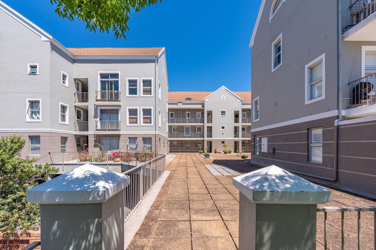 A view of the apartment complex courtyard featuring paved walkways, metal railings, and multi-story residential blocks with balconies.