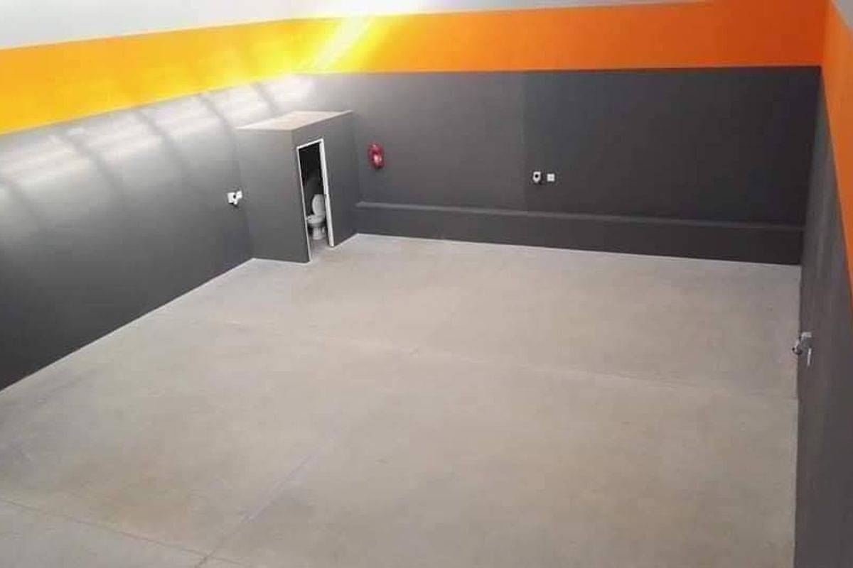 Spacious industrial utility area featuring smooth concrete flooring, painted walls with high-visibility accents, and a private enclosed toilet facility.