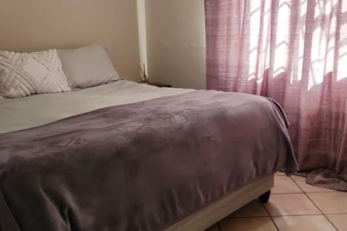 A bedroom featuring tiled flooring and a window with curtains, providing a functional and comfortable living space.