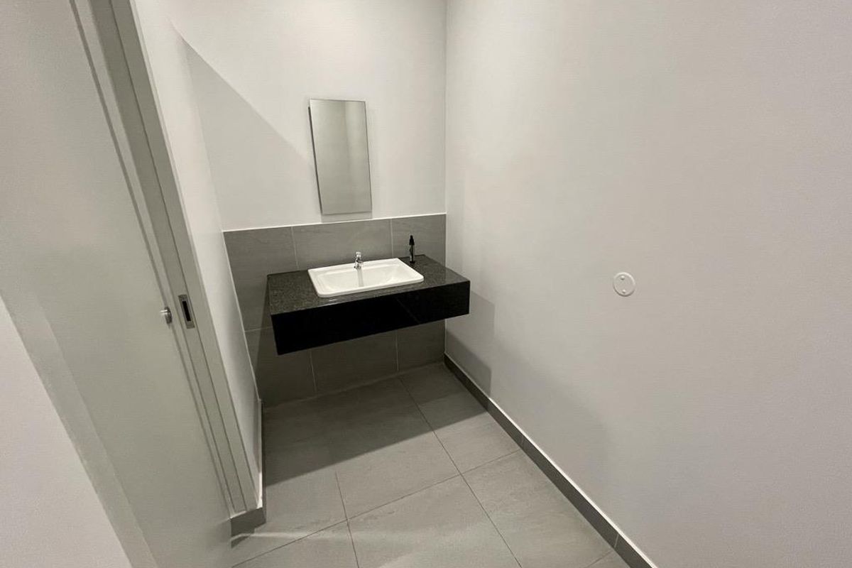 A clean, modern powder room featuring a wall-mounted vanity with a stone countertop, integrated basin, and neutral floor tiling.