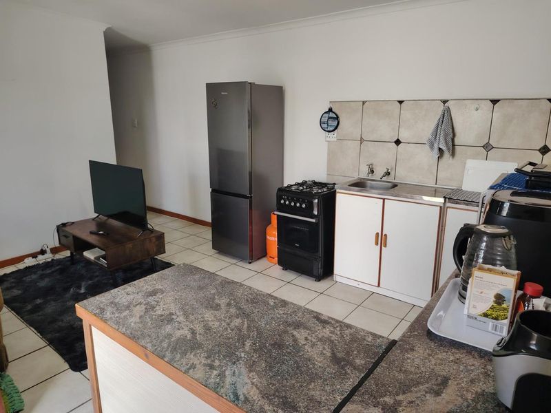 Open-plan living and kitchen area featuring tiled flooring, a compact kitchen setup with gas stove, and a functional kitchen island.