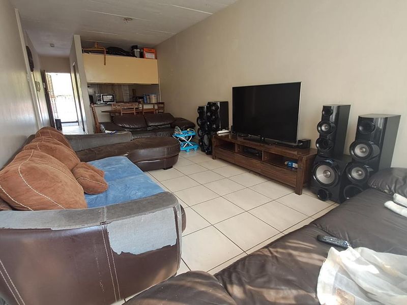 Open plan living area featuring tiled flooring and a view through to the kitchen area.