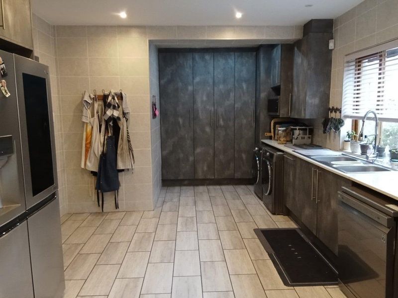 A modern, well-appointed laundry room featuring extensive built-in cabinetry, tiled finishes, and integrated laundry appliances.