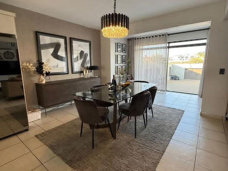 A well-maintained dining area featuring tiled flooring, a modern pendant light fixture, and large sliding glass doors providing access to the outdoor space.