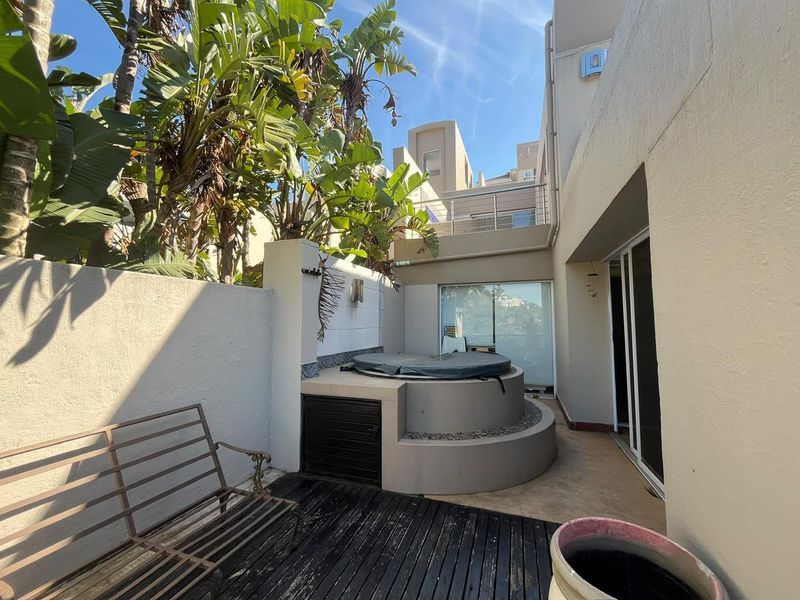 Outdoor patio area featuring a built-in jacuzzi, timber decking, and direct access to the interior through sliding glass doors.